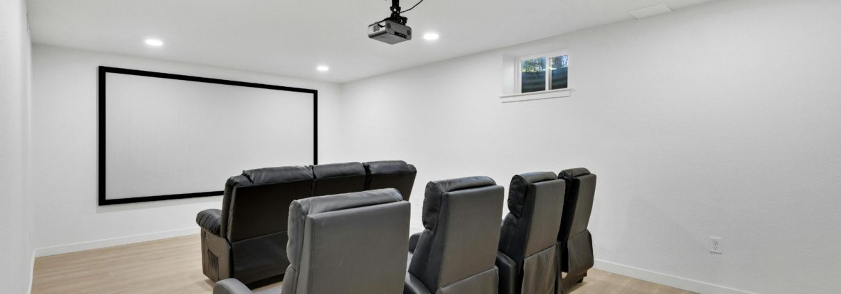 leather reclining seats with a projector screen in a finished basement - We Finish Basements 2026 Basement Home Theater Guide