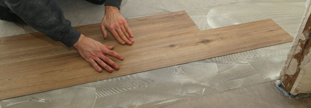 person gluing down flooring onto concrete - We Finish Basement moisture resistant basement flooring